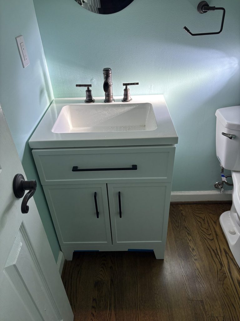 | AFTER — new vanity with the homeowner's existing faucet reinstalled | New white bathroom vanity with the original faucet reinstalled by ARC Plumbing in Haddon Hall, Apex, NC |
