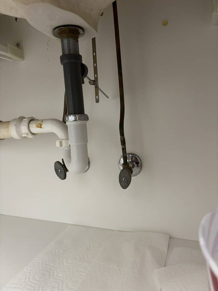 BEFORE — old supply lines under the sink | Old faucet supply lines under a bathroom sink in Raleigh, NC |