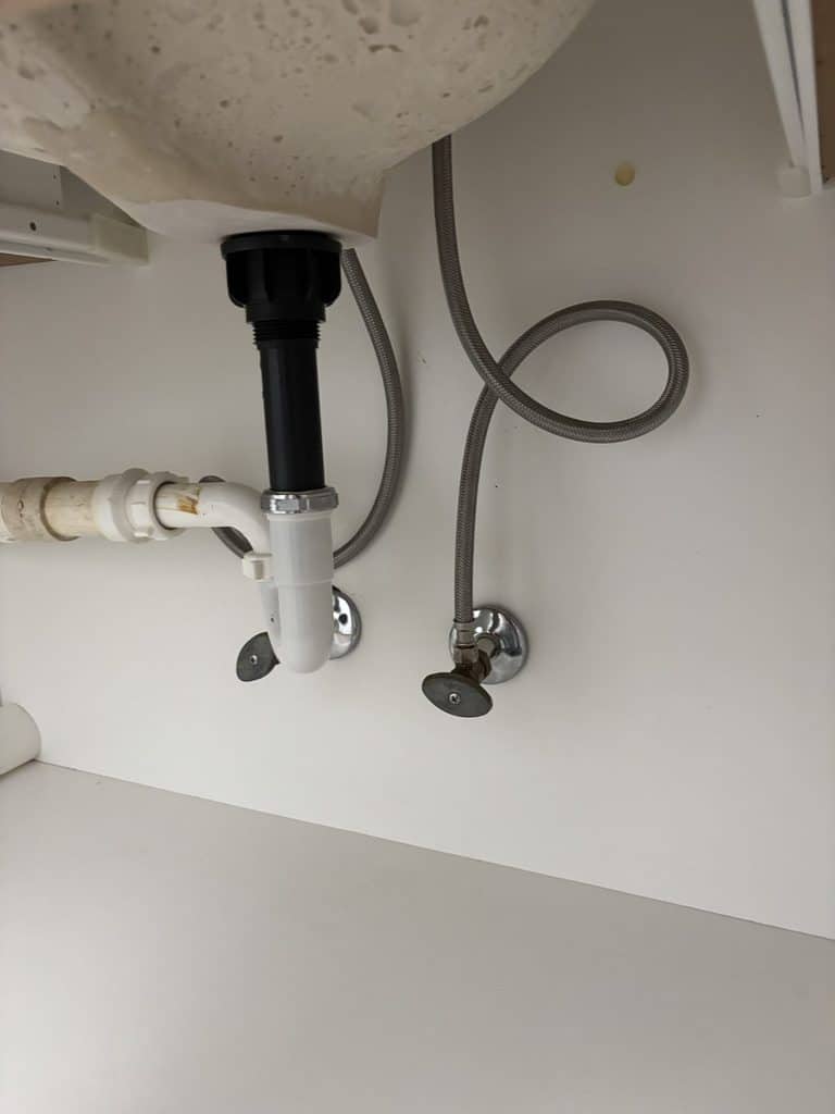AFTER — new braided supply lines | New braided faucet supply lines under a bathroom sink installed by ARC Plumbing in Raleigh, NC |