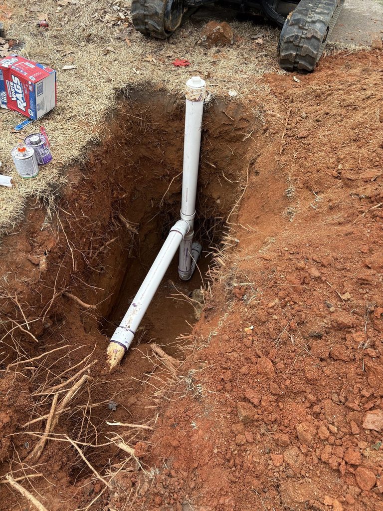 New PVC sewer pipe and cleanout riser installed by ARC Plumbing in an excavation in Wake Forest, NC