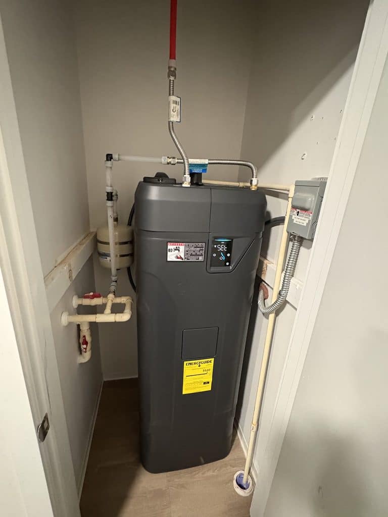 | AFTER — one Essency in place of both tanks, shelf removed | New Essency water heater installed by ARC Plumbing in a Raleigh apartment utility closet |