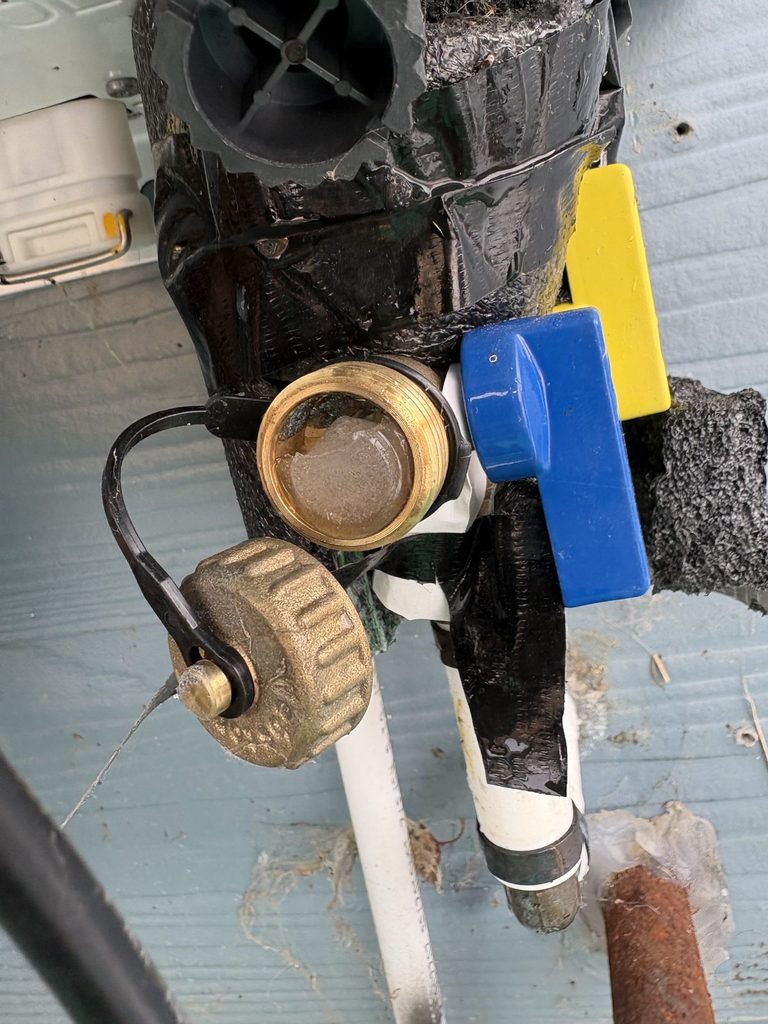 BEFORE — ice on the service valves under the unit | Ice-covered service valves under a frozen Navien tankless water heater in Angier, NC |