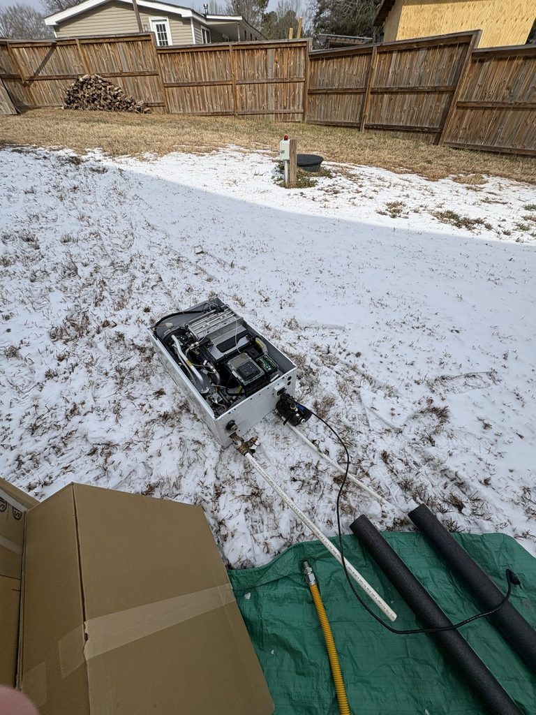 DURING — the old Navien off the wall | Freeze-damaged Navien tankless water heater removed from an Angier, NC home |